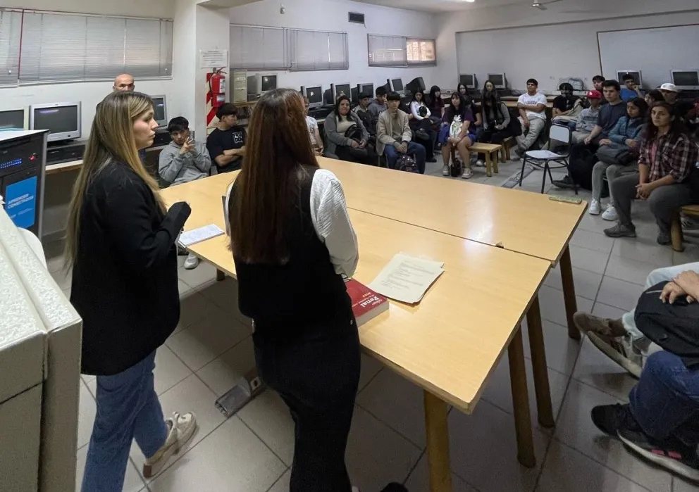 Dos de las estudiante ante alumnos de la secundaria, explicando cómo funciona el juicio por jurados 