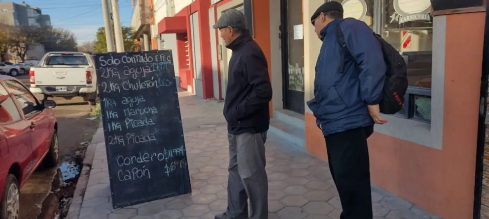 Dos personas miran las ofertas de una carnicería en Viedma.