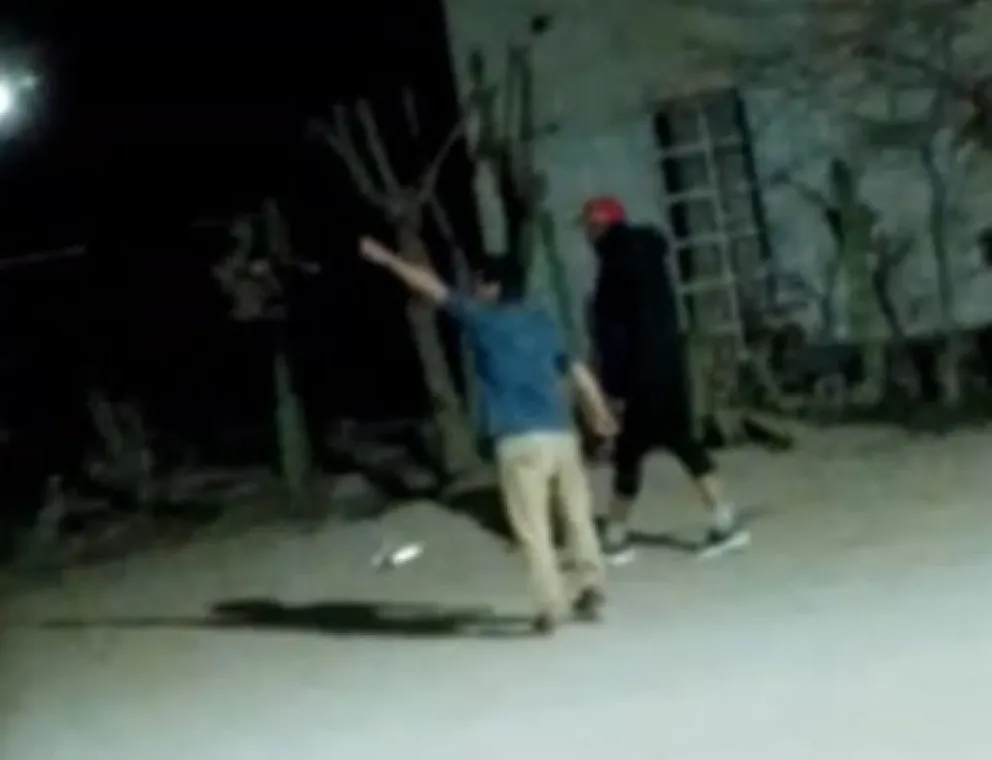 La víctima señalando hacia un costado y el agresor de espalda, con una gorra roja. Captura de video. 