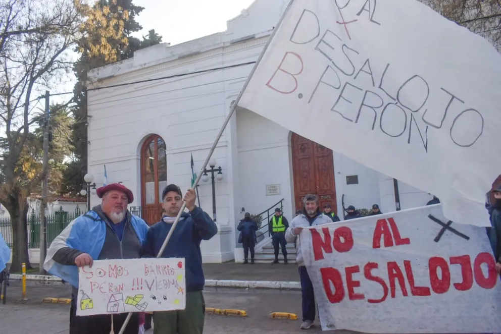 Familias que viven en terrenos pertenecientes a YPF se manifestaron este lunes frente al edificio municipal de Viedma con banderas y carteles en los que expresaron su rechazo a un eventual desalojo. Fotos: Vanesa Schwemmler.