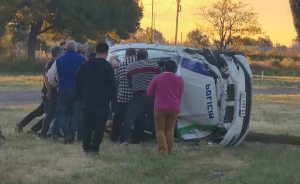 Vecinos y automovilistas se acercaron inmediatamente para auxiliar a los efectivos atrapados tras el vuelco del móvil policial. Fotos: Gentileza Lo Principal. 